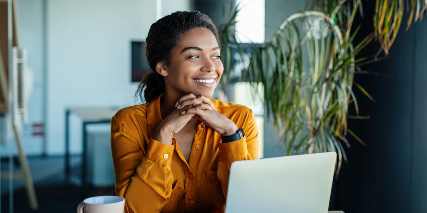 A smiling young woman sitting at a desk.