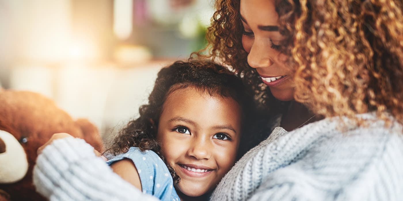 A mother embracing her adolescent daughter.